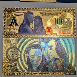 May include: Gold-colored novelty bills featuring Avatar characters. One bill is a $100 bill, and the other is a $1,000,000 bill. The bills have detailed illustrations of the characters and the text "GOLD" and "AVATAR".