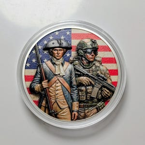 May include: A circular commemorative coin featuring a relief design of a Revolutionary War soldier in a blue coat and tricorn hat alongside a modern soldier in tactical gear, both set against a background of the American flag in red, white, and blue.