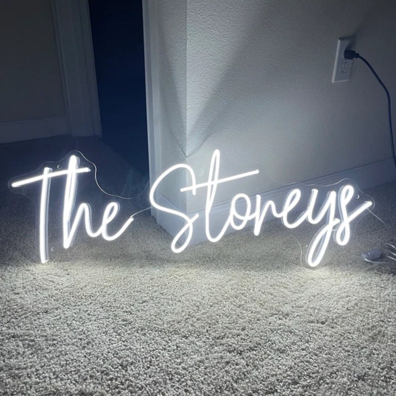 Puede incluir: Letrero de ne&oacute;n blanco con el texto "The Stoneys" en una fuente cursiva.