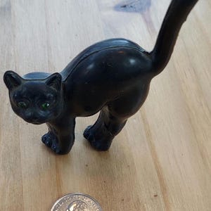 Vintage black cat with green eyes , plaster covered by black plastic. Does have a crack on leg.