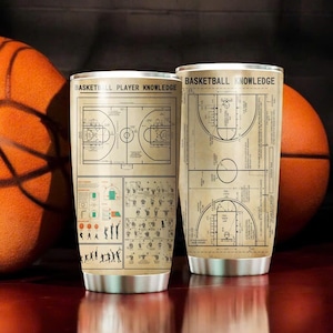 May include: Two stainless steel tumblers with a basketball court diagram and player knowledge guide printed on them. The tumblers are on a wooden surface with a basketball on either side.