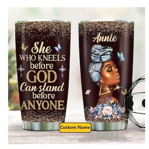 May include: A brown and gold tumbler with a quote that reads "She who kneels before God can stand before anyone". The tumbler has a gold glitter finish and features a black woman with a blue head wrap and gold earrings. The tumbler has a custom name tag that says "Annie".