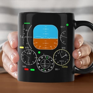 Könnte beinhalten: Schwarze Keramik-Kaffeetasse mit einem Design eines Flugzeugcockpit-Instrumentenpanels. Das Design beinhaltet einen Kompass, einen Höhenmesser und andere Messgeräte. Der Text "Things For Home Design" ist auf der Unterseite der Tasse aufgedruckt.