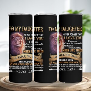 May include: Black insulated tumbler with a lion illustration and text that reads "TO MY DAUGHTER, NEVER FORGET THAT I LOVE YOU." The tumbler has a black background and a silver rim. The text also includes "LOVE, DAD."
