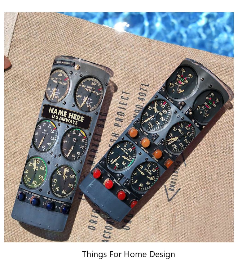 May include: Two gray metal can coolers with a vintage airplane cockpit instrument panel design. The can coolers feature various gauges, dials, and labels, including "NAME HERE" and "U.S. AIRWAYS".