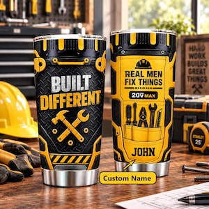 Peut inclure: Deux gobelets en acier inoxydable au design industriel jaune et noir. L'un affiche le texte BUILT DIFFERENT avec un marteau et une clé. L'autre présente REAL MEN FIX THINGS, 20V MAX, des illustrations d'outils et le prénom JOHN.