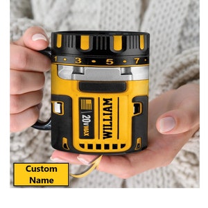 May include: Yellow and black mug with a drill design. The mug has a black handle and a silver band around the middle. The mug says "WILLIAM 20V MAX" on the side. The mug has a custom name area on the bottom.