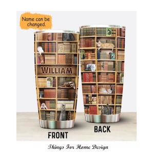 Op de afbeelding: Een roestvrijstalen tumbler met een gepersonaliseerde naam, "WILLIAM", gedrukt op de voorkant. De tumbler heeft een ontwerp van een boekenkast vol boeken en katten.