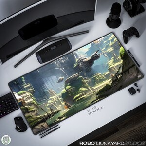 以下が含まれることがあります： 未来都市の風景が印刷された、大きく長方形の黒いゲーミングマウスパッド。シーンには、緑の葉の生えた頂上を持つ大きな灰色の建物、川、飛行中の乗り物が描かれています。マウスパッドのサイズは79cm x 39cmです。