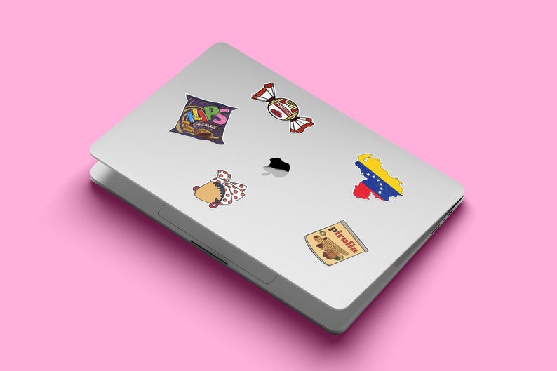 May include: A silver laptop with five stickers on it. The stickers are of a bag of crisps, a sweet, a woman with a flower in her hair, a map of Venezuela, and a box of Pirulin.
