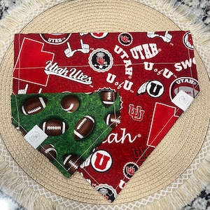 May include: Two red and green dog bandanas with the University of Utah logo and the words "Utah Utes" and "U of U".