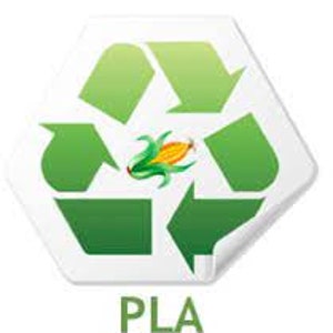 May include: A white, hexagonal sticker featuring a green recycling symbol with a corn stalk in the center. The word "PLA" is printed in green below the symbol. The sticker has a slight curve on the bottom right corner.