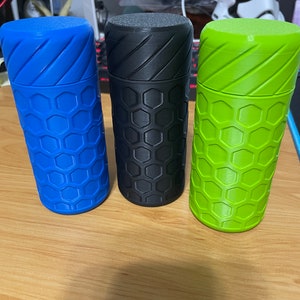 May include: Three cylindrical containers with a honeycomb pattern. The containers are blue, black, and green.