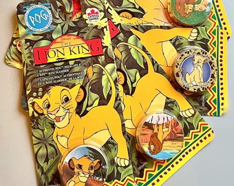 May include: A collection of vintage Lion King POGs and collectible buttons. The packaging features Simba and other characters from the animated film. The buttons have various designs, including Simba and other characters. The background has a jungle theme.
