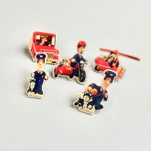 Könnte beinhalten: Ein Set mit sechs Postman Pat-Charakter-Ansteckern. Die Anstecker zeigen Postman Pat in seinem roten Lieferwagen, auf seinem Motorrad, in seinem Hubschrauber und mit seiner Katze Jess. Die Anstecker sind aus Metall und haben eine glänzende Oberfläche.