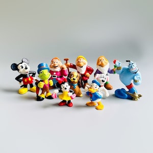 May include: A collection of ten small plastic figurines of Disney characters, including Mickey Mouse, Donald Duck, Goofy, and Snow White. The figurines are brightly colored and feature detailed designs.