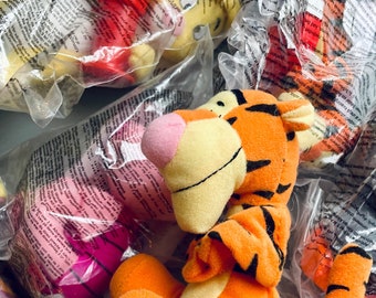 May include: A collection of Winnie the Pooh plush toys in individual plastic bags. The toys include Tigger, Piglet, Eeyore, and Winnie the Pooh. The toys are all in good condition and would be a great addition to any Winnie the Pooh fan's collection.