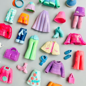 以下が含まれることがあります： カラフルなプラスチック製のドール服とアクセサリーのコレクションです。アイテムには、さまざまなトップス、ボトムス、スカート、帽子、靴、バッグが含まれています。服はすべて異なる色とパターンで、一部はグリッターやスパンコールが付いています。