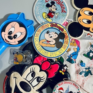 May include: A collection of vintage Disney memorabilia featuring Mickey Mouse and Minnie Mouse. The collection includes a pin, a coin purse, a mirror, a button, a patch, and an ornament. The items are all in various colors and feature different designs of Mickey and Minnie Mouse.