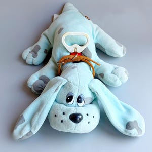 May include: A white ceramic mug with a black handle and the text "But First, Coffee" in a bold, black font. The mug is set against a blurred background, suggesting a cozy setting.