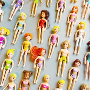 以下が含まれることがあります： さまざまな髪型と衣装の小さな人形のコレクション。人形は黄色、ピンク、紫、緑など、さまざまな色があります。水着を着ている人形もいれば、上半身裸の人形もいます。