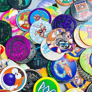 Könnte beinhalten: Eine Sammlung von bunten, runden, aus Plastik gefertigten Spielsteinen mit verschiedenen Comicfiguren und Designs. Die Steine sind in verschiedenen Farben gehalten, darunter Rot, Blau, Grün, Gelb und Lila. Die Steine haben einen Durchmesser von etwa 5 cm. Jeder Stein ist einzigartig, aber sie alle haben ein ähnliches Design. Die Steine sind alle aus Plastik gefertigt und haben eine glatte, glänzende Oberfläche.