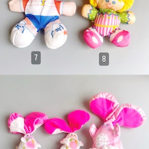 Pu&ograve; includere: Una collezione di giocattoli di peluche vintage, tra cui due bambole con capelli gialli e un cappello verde, e tre giocattoli a forma di coniglio con orecchie e dettagli rosa. Giocattoli morbidi e colorati.