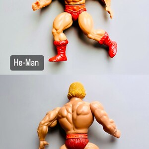 May include: A vintage He-Man action figure with a muscular build, blond hair, and a red loincloth. The figure is posed in a running stance with both legs bent and feet raised. The figure is wearing red boots with fur trim.