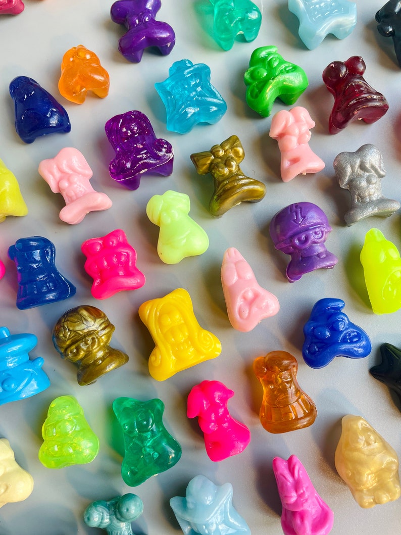 May include: A collection of colorful plastic figurines in various shapes and sizes. The figurines are made of translucent plastic and have a glossy finish. Some of the figurines are shaped like animals, while others are shaped like people or objects.