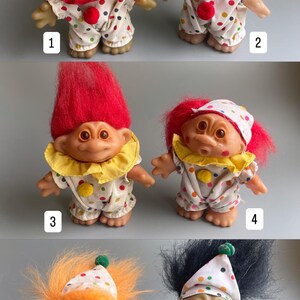 Pu&ograve; includere: Sei bambole troll colorate vestite da clown. Ogni bambola ha i capelli di un colore diverso e un costume da clown bianco e rosso con pois colorati. Le bambole sono numerate da 1 a 6.