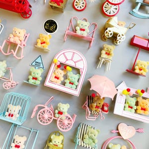May include: A collection of miniature teddy bears in various poses and settings. The bears are in different colors, including yellow, green, and tan, and are accessorized with bows and miniature furniture like swings, benches, and carriages. Some bears hold balloons.