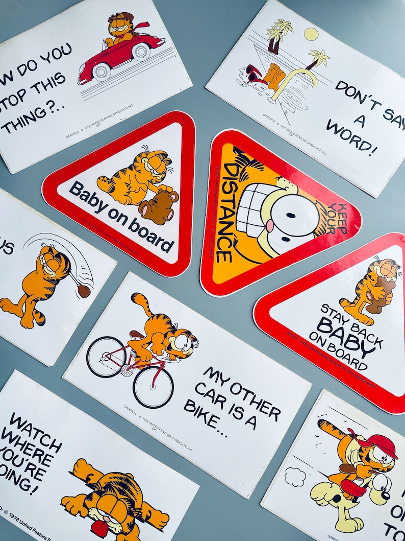 Puede incluir: Un conjunto de diez pegatinas de coche de Garfield. Las pegatinas muestran a Garfield en varias poses y frases, incluyendo "Beb&eacute; a bordo", "Mant&eacute;n la distancia", "Qu&eacute;date atr&aacute;s, beb&eacute; a bordo", "Mi otro coche es una bicicleta", "Mira por d&oacute;nde vas", y "&iexcl;No digas ni una palabra!"