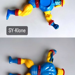 May include: A blue and yellow action figure with a red and yellow helmet. The figure is lying on its back with its arms outstretched. The figure is labeled "SY-Klone".