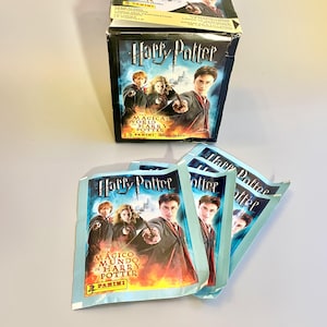 May include: A box of Harry Potter sticker packs with a blue and white design. The box features a picture of Harry Potter and his friends. The text on the box reads "The Magical World of Harry Potter".