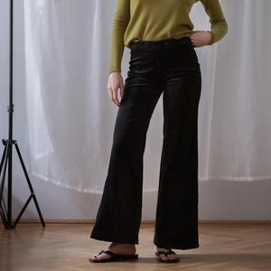Op de afbeelding: Een zwarte wijde broek van corduroy. De broek heeft een hoge taille en een wijde pijpopening.