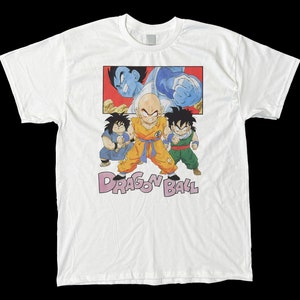 May include: White t-shirt with a colorful graphic print of characters from the Dragon Ball anime series. The graphic features Goku, Gohan, and Vegeta in a fighting pose. The text "Dragon Ball" is printed below the graphic.