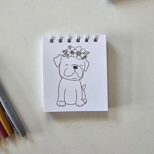 May include: A black and white line drawing of a dog wearing a flower crown. The dog is sitting with its legs crossed and has a happy expression on its face.