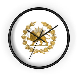 May include: A circular wall clock with a black frame. The clock face displays a gold emblem of a lion holding a sword, encircled by a wreath and sunburst design, on a white backdrop. The clock hands are black.