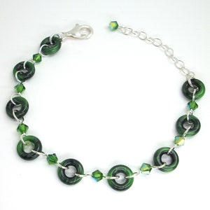 May include: A green glass bead bracelet with silver chain and green crystal accents.