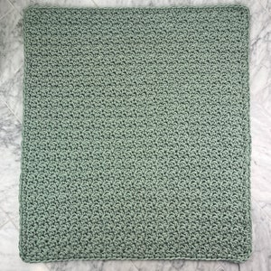 May include: A soft, sage green crocheted blanket with a simple stitch pattern.