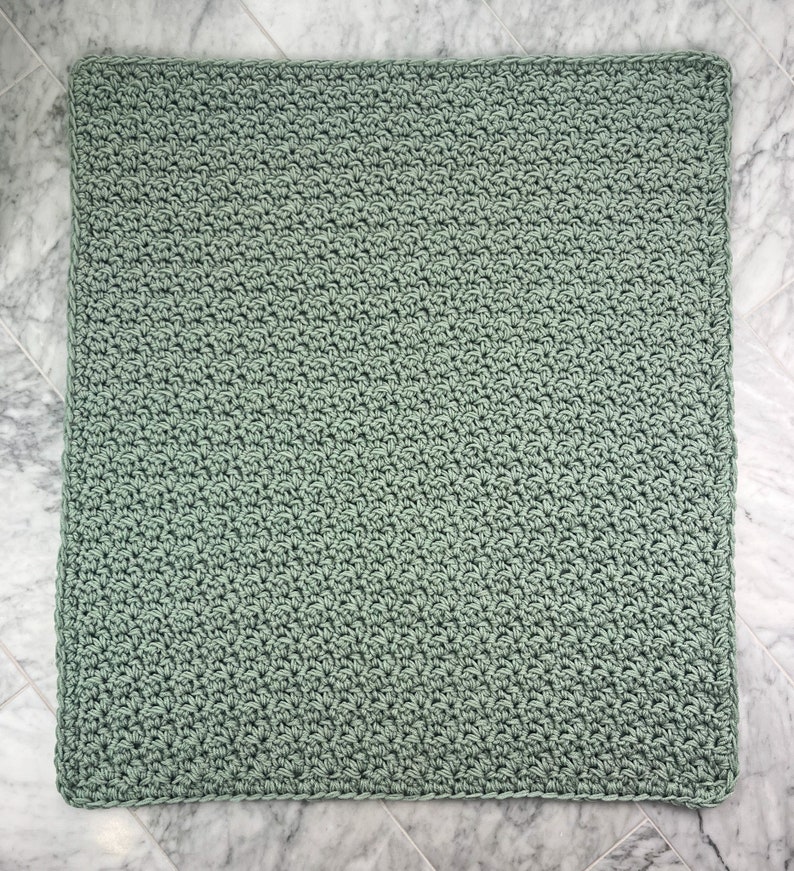 May include: A soft, sage green crocheted blanket with a simple stitch pattern.