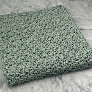 May include: A soft, sage green crocheted blanket with a textured, woven pattern.