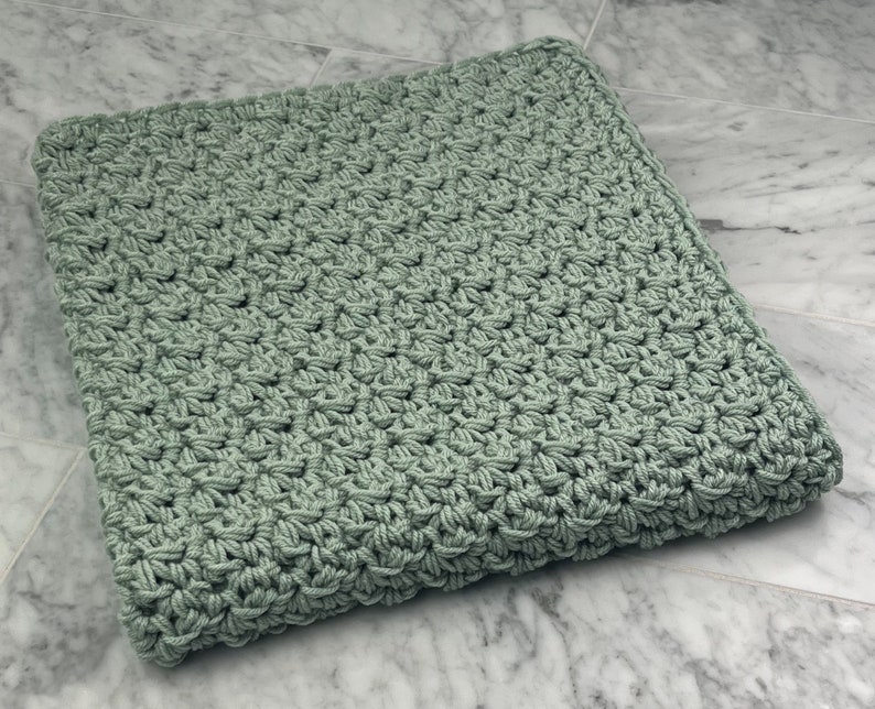 May include: A soft, sage green crocheted blanket with a textured, woven pattern.