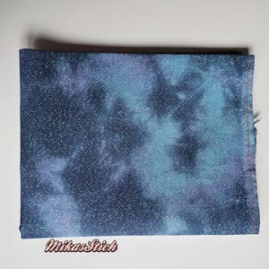 Könnte beinhalten: Ein Stück blauer und weißer Batikstoff mit einer gesprenkelten Textur. Der Stoff ist in der Mitte gefaltet und hat einen weißen Rand.