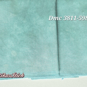 Puede incluir: Una pieza de tela color verde azulado claro con una textura moteada y variada. La tela presenta el texto impreso Dmc 3811-598 en la esquina superior derecha y el texto MikasStich en la esquina inferior izquierda, ambos en fuente serif blanca.