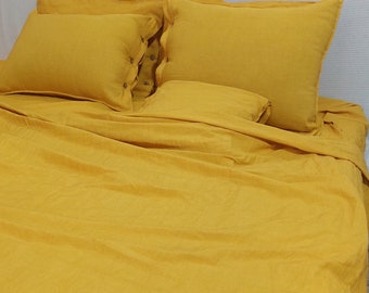 May include: A yellow linen duvet cover with two matching pillowcases and a smaller pillow. The bedding is made of a soft, natural fabric and has a relaxed, casual look.