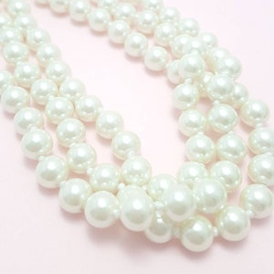 May include: A white pearl necklace with multiple strands of pearls. The pearls are round and smooth, and the necklace is strung on a white thread.