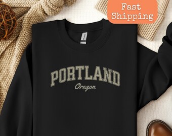 May include: Black sweatshirt with a white graphic print that says "PORTLAND Oregon" in a vintage collegiate style font.