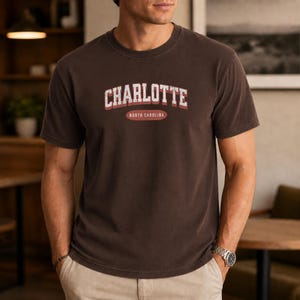 Brown t-shirt with "Charlotte North Carolina" text in distressed white and red.