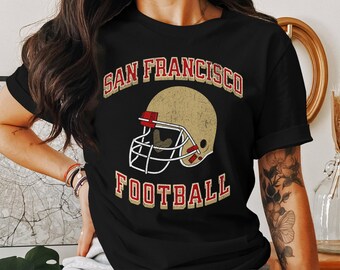 May include: Black t-shirt with a vintage-style graphic of a football helmet and the text "San Francisco Football".